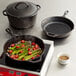 A Lodge cast iron skillet with asparagus and tomatoes cooking on a stove.