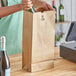 A woman pouring wine into a brown paper bag on a counter.