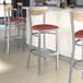 Lancaster Table & Seating Boomerang bar stools with burgundy vinyl seats and driftwood backs at a restaurant counter.