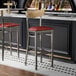 Two Lancaster Table & Seating bar stools with burgundy vinyl seats and driftwood backs at a black counter.
