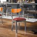 A metal chair with a burgundy vinyl seat and a cherry wood backrest.