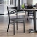 A black cross back chair with a black wood seat and a detached seat design.