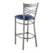 A Lancaster Table & Seating metal bar stool with a navy blue cushioned seat.