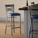 A Lancaster Table & Seating navy vinyl padded cross back bar stool on a table.