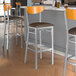 A group of Lancaster Table & Seating bar stools with dark brown vinyl seats and cherry wood backs.