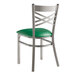 A Lancaster Table & Seating metal cross back chair with a green cushion.