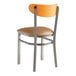 A Lancaster Table & Seating Boomerang clear coat finish chair with a light brown vinyl cushion and cherry wood back on a metal frame.