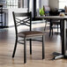 A black cross back chair with a dark brown vinyl padded seat.