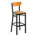 A bar stool with a black metal frame, light brown vinyl seat, and a cherry wood backrest.