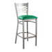 A Lancaster Table & Seating clear coat metal bar stool with a green vinyl padded seat.