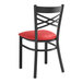 A black metal Lancaster Table & Seating Cross Back chair with a red cushion.