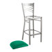 A Lancaster Table & Seating metal cross back bar stool with a green vinyl padded seat.