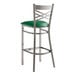 A Lancaster Table & Seating clear coat cross back bar stool with a green vinyl padded seat.