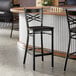 A black finish cross back bar stool with a black wood seat and detached seat design.
