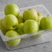A clear plastic container filled with Granny Smith apples.