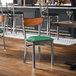 A metal chair with a green vinyl seat and an antique walnut wood backrest.