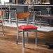 A metal chair with a red vinyl seat and an antique walnut wood backrest.