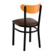 A black metal chair with a dark brown vinyl seat and a curved cherry wood backrest.