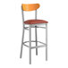 A Lancaster Table & Seating bar stool with a red vinyl seat and cherry wood back.