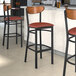 Three Lancaster Table & Seating Boomerang Series bar stools with burgundy vinyl seats and antique walnut backs at a restaurant counter.
