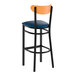 A bar stool with a black metal frame, navy vinyl seat, and cherry wood backrest.