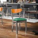 A metal chair with a green vinyl seat and a cherry wood backrest.