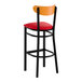 A bar stool with a black metal frame, red vinyl seat, and a cherry wood backrest.