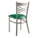 A Lancaster Table & Seating metal cross back chair with a green vinyl padded seat.