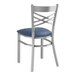 A Lancaster Table & Seating metal cross back chair with a navy blue cushion.