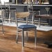 A metal chair with a navy vinyl seat and a driftwood-finished wooden backrest.