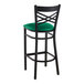 A Lancaster Table & Seating black cross back bar stool with a green vinyl padded seat.