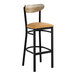 A bar stool with a black metal frame, light brown vinyl seat, and a curved driftwood backrest.