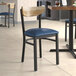 A Lancaster Table & Seating Boomerang chair with a navy cushion and driftwood back on a table in a restaurant.
