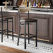 A black finish bar stool with a dark brown vinyl seat and a driftwood backrest.