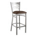 A Lancaster Table & Seating clear coat finish cross back bar stool with a dark brown vinyl padded seat.