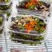A close up of Dart ClearPac plastic containers filled with salad on a counter.