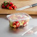 A Dart ClearPac plastic deli container filled with fruit on a counter.