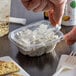 A person puts a Dart deli container of food on a table.