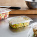 A variety of Dart plastic containers with food in them on a counter.