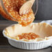 A bowl of Brill Diced Apple Pie Filling being poured into a pie crust.