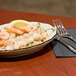 A CAC ivory china platter with shrimp, rice, and lemon on it with silverware on the table.