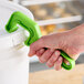 A hand holding a green Warner Plastic Pail Opener.