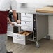 A man wearing gloves placing food in a ServIt drawer.