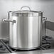 A Vollrath stainless steel domed cover on a large silver pot on a stove.