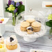 A table with desserts and cookies displayed under a clear acrylic dome cover.