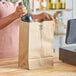 A woman using a Duro brown paper bag to carry a bottle of wine.