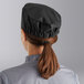 A woman wearing a large black Choice cloth chef hat.