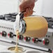 A person pouring batter from a Vollrath Dripcut server into a cupcake tin.