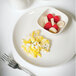 A Tuxton eggshell china plate with eggs and fruit on it.