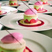 A group of RAK Porcelain ivory porcelain flat plates with desserts on them.